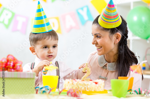 Kid boy celebrating birthday holiday. Mom looking happily to her