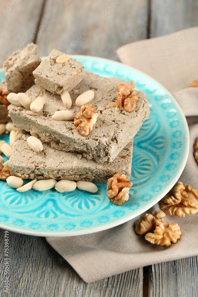 Fototapeta premium Sunflower halva with nuts on plate, on wooden background