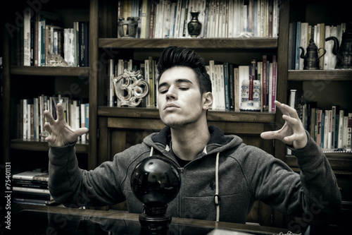 Photos Young man predicting the future by looking into crystal ball