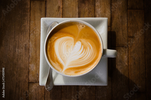 cup of cappucchino over wooden table photo