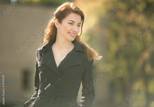 golden lady looking down in trench coat autumn time