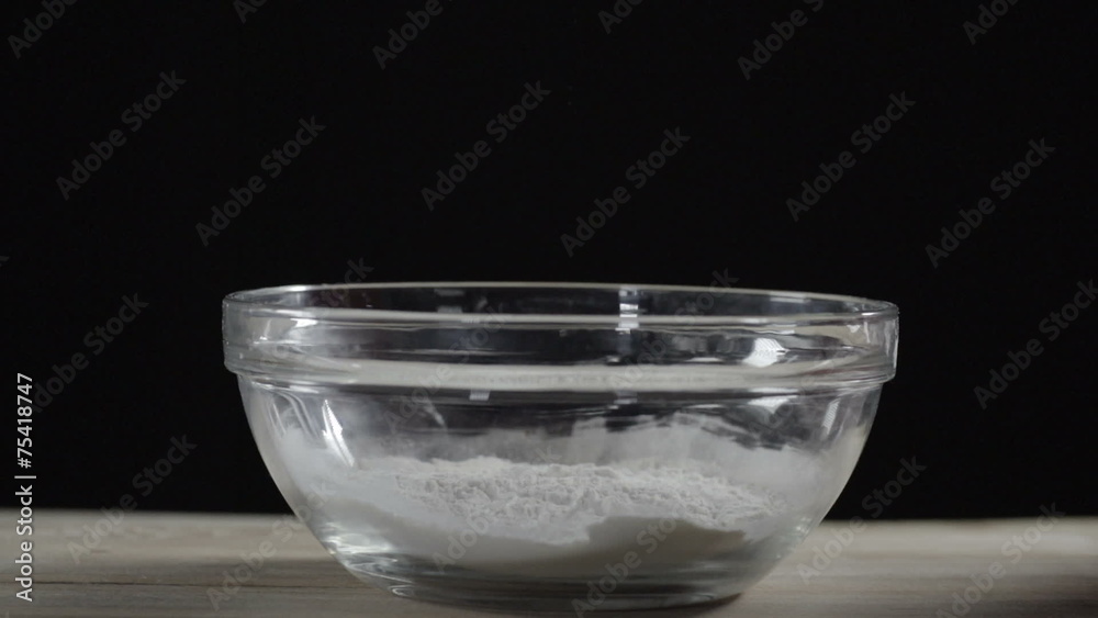 Sifting flour into bowl on table black background slow motion Sifting flour into bowl on table black background slow motion