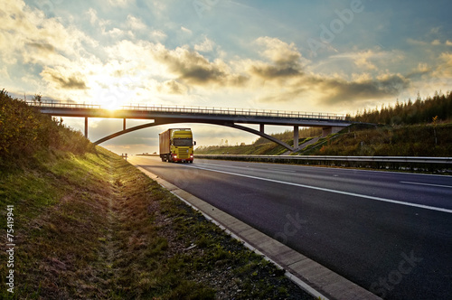 Sunset over highway, bridge and riding a yellow truck