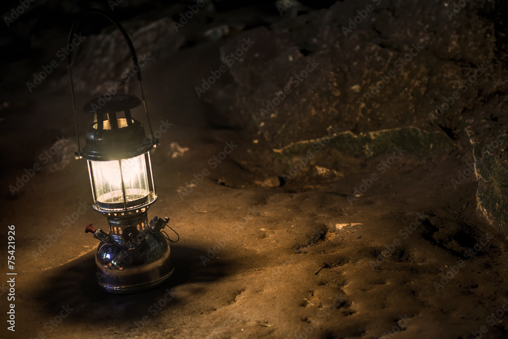 The old antique storm lantern in a cave - obrazy, fototapety, plakaty 