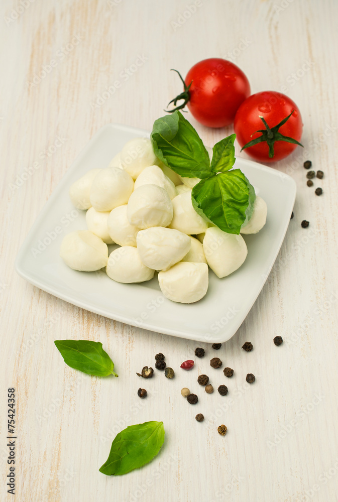 mozzarella , cherry tomatoes and basil on a wooden table