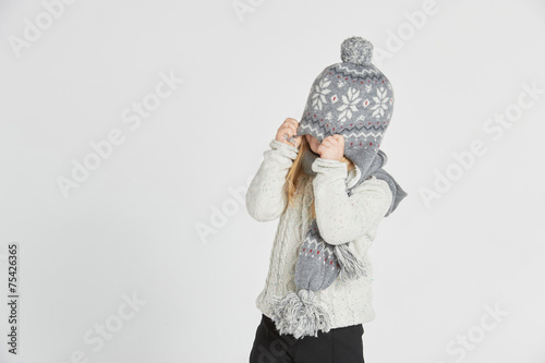 Beautiful blond girl playing in the winter warm hat and scarf on