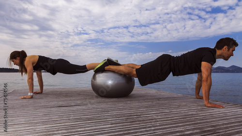Man and woman doing push-ups with exercice ball photo