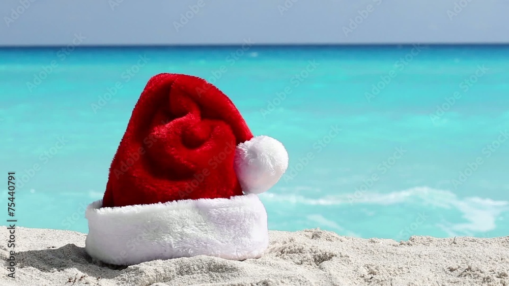 Santa Hat on white sandy beach with Caribbean sea background Santa Hat on white sandy beach with Caribbean sea background