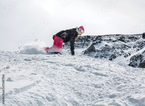 Woman snowboarder in motion in mountains photo