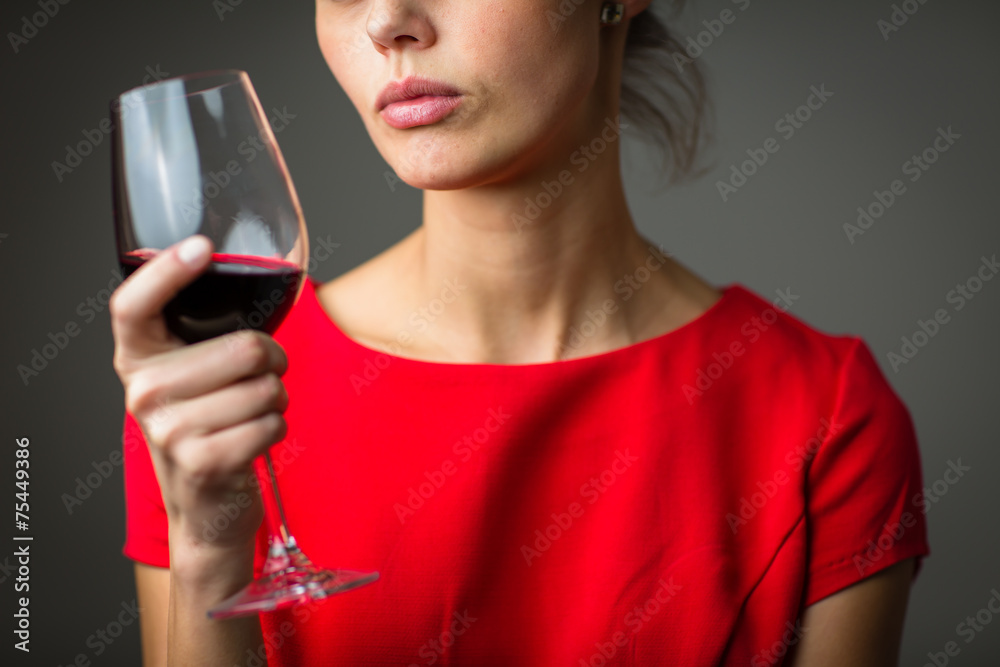 Elegant young woman in a red dress, having a glass of red wine Elegant young woman in a red dress, having a glass of red wine