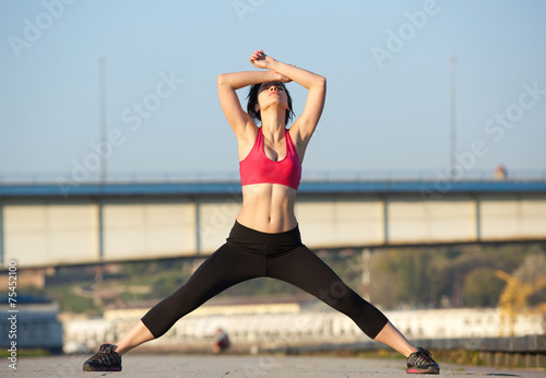 Active young sports woman stretching body muscles
