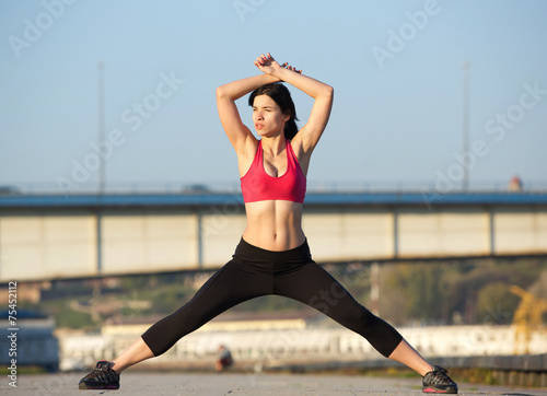 beautiful young woman wearing gym clothes and stretching muscles