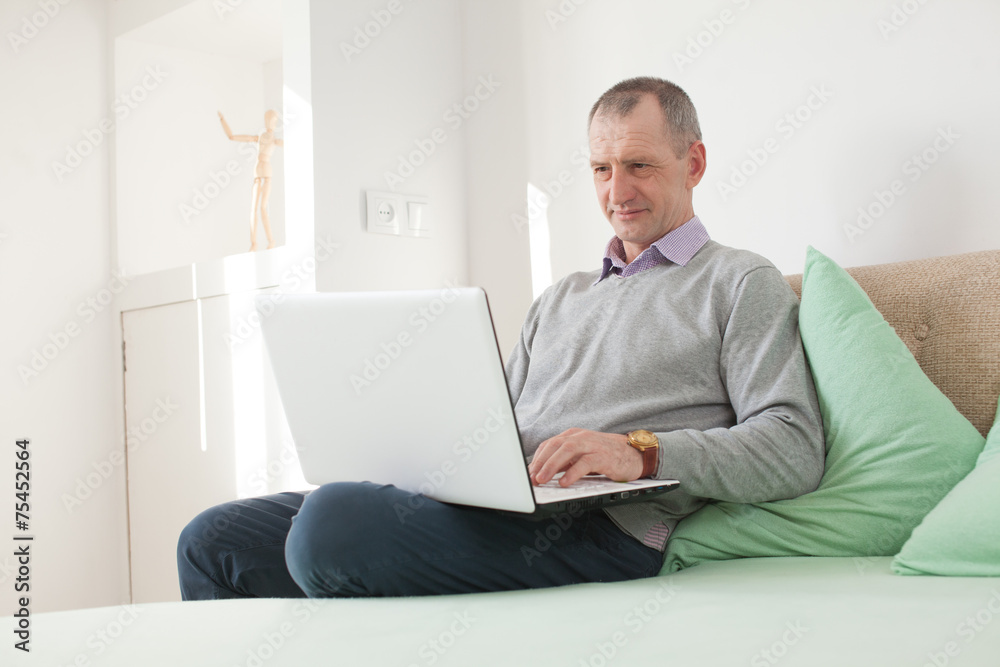 Adult man using a laptop at home Adult man using a laptop at home