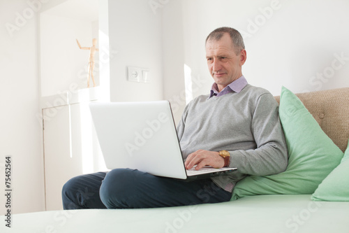 Adult man using a laptop at home © rasstock