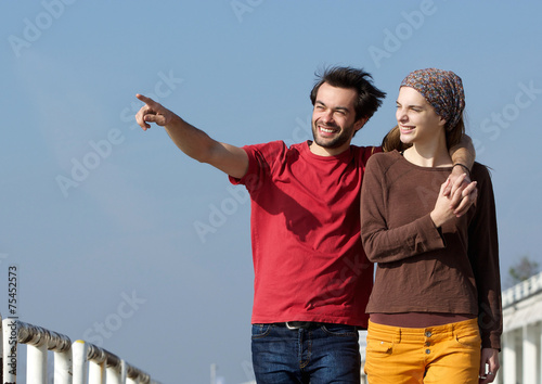 Happy young couple walking outdoors and pointing