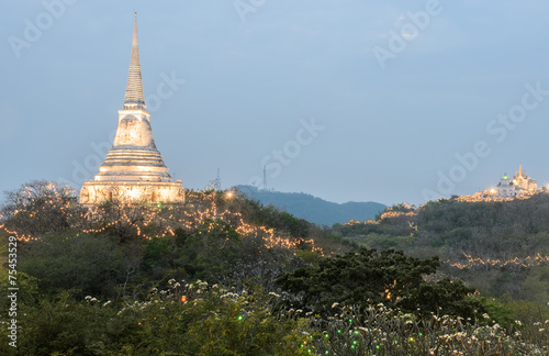 White pagoda illuminated on hill at sunset