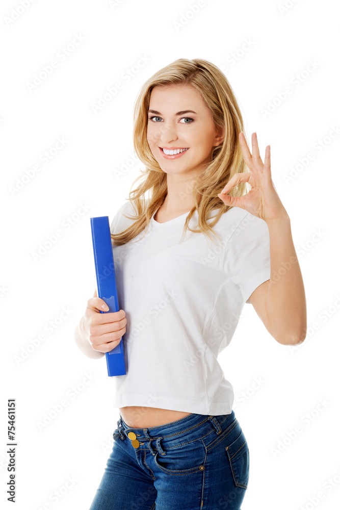 Young woman making ok sign holding binder Young woman making ok sign holding binder