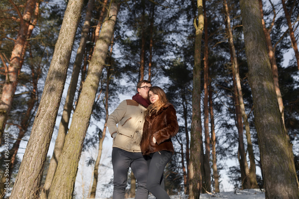 Cheerful couple in a pine forest in winter Cheerful couple in a pine forest in winter