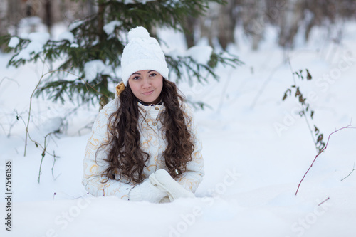 young girl lying in the snow and smile in winter forest