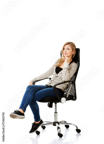 Young woman sitting on armchair touching chin