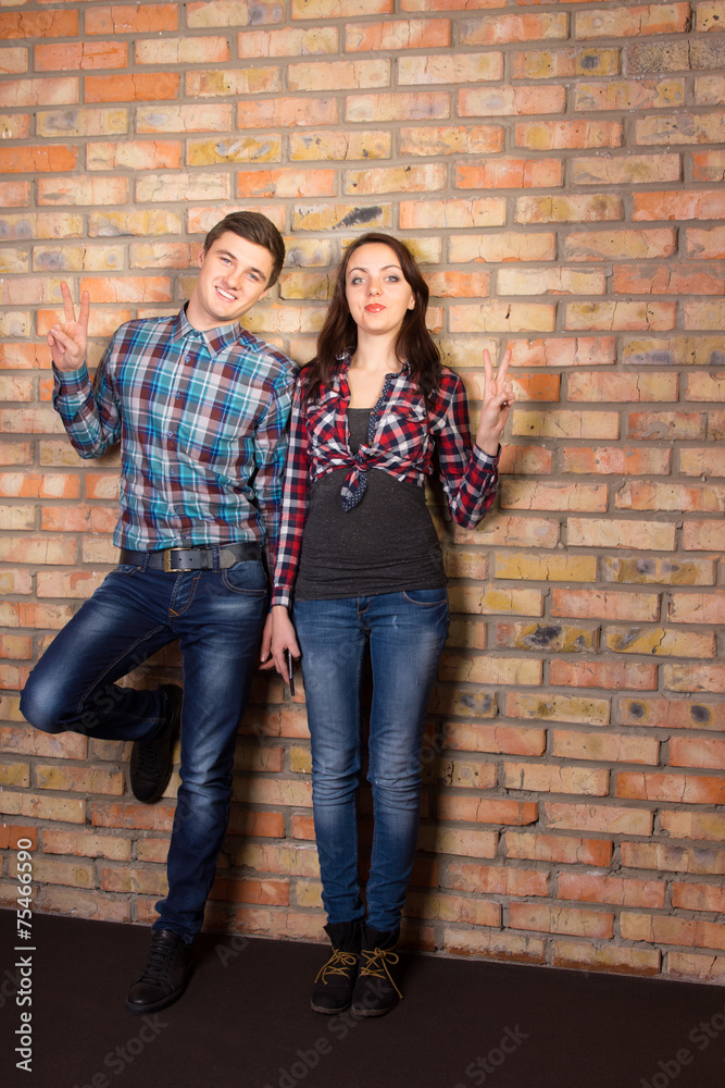 Young White Couple Posing at Brick Wall