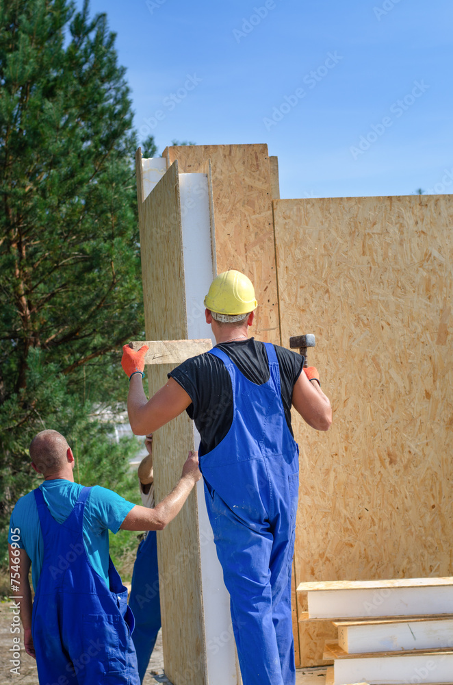 Two builders installing a wooden wall panel