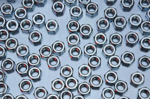 Shiny nuts on metal surface abstract industry background