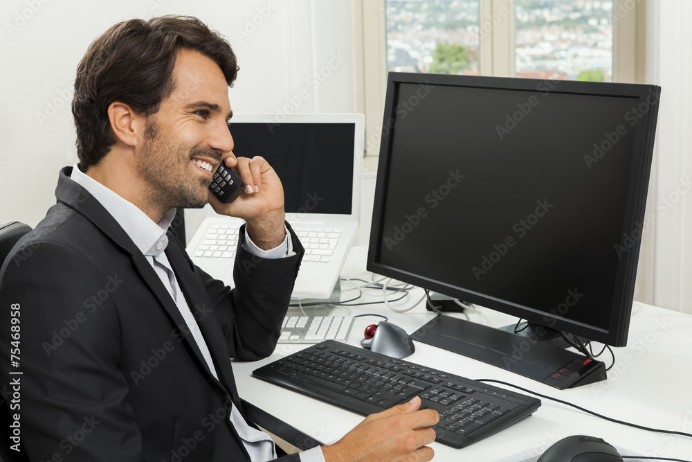 Young handsome man sitting at his desk in the office Young handsome man sitting at his desk in the office