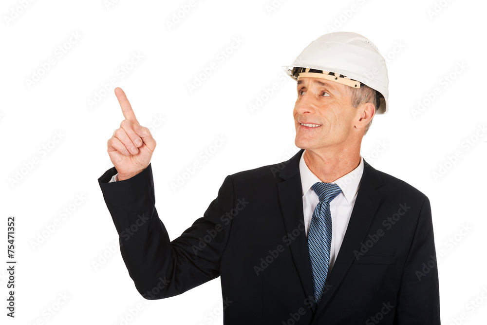 Smiling businessman with hard hat pointing up Smiling businessman with hard hat pointing up