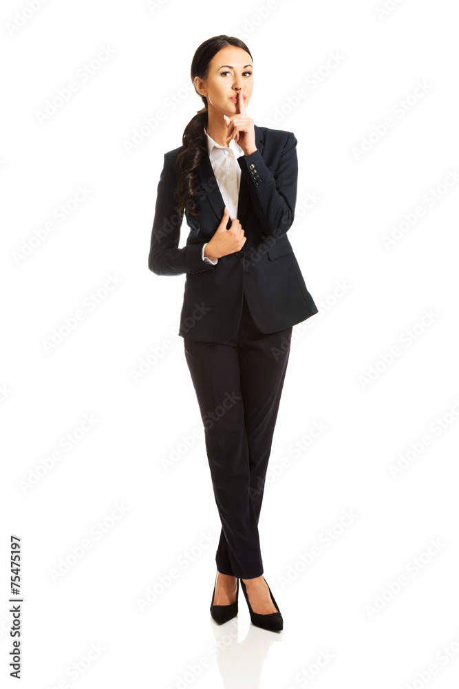 Full length businesswoman making silent sign Full length businesswoman making silent sign