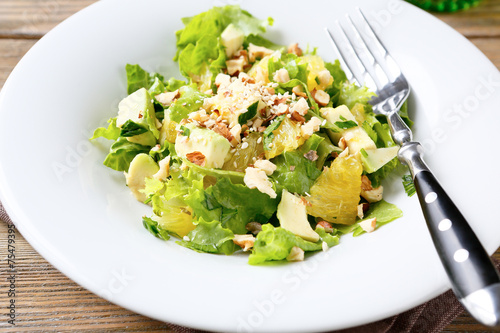 Salad with Avocado, Lettuce, Orange and Nuts on a white bowl