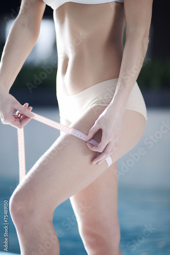 A slim girl measuring her waist, closeup 