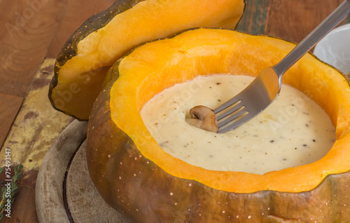 Cheese fondue in a roasted pumpkin with chestnut mushroom on a f