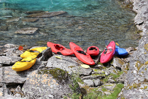 Seven kayaks on the river bank.