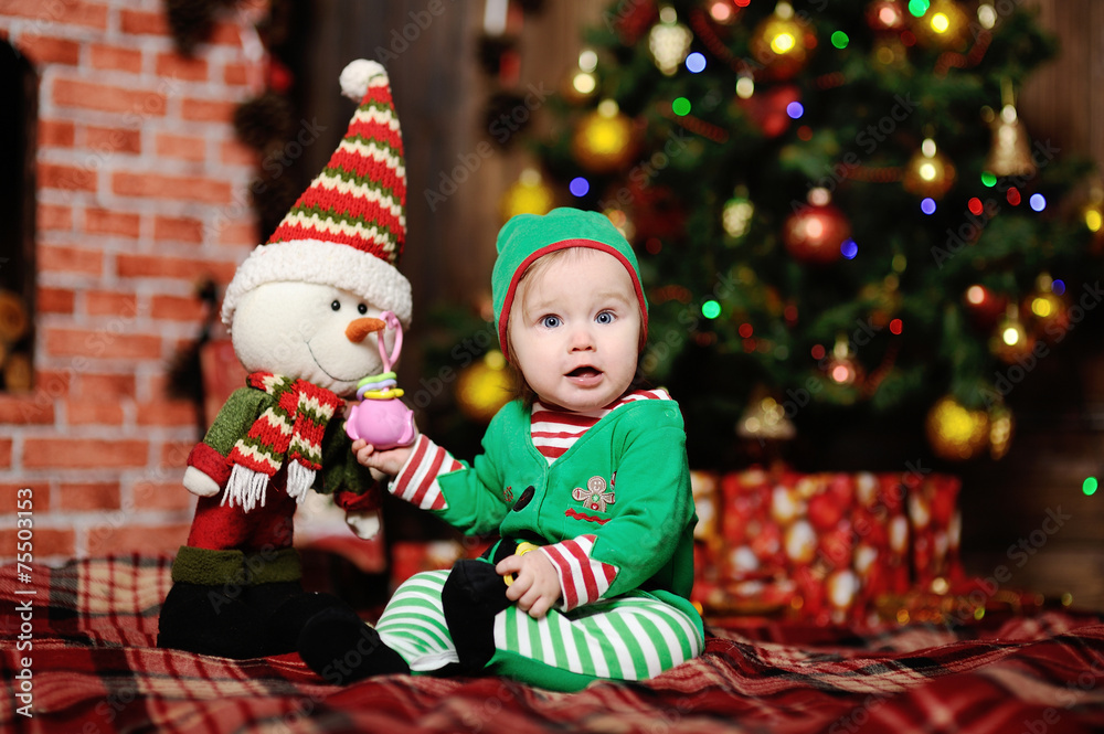 A child dressed as an elf sitting on a plaid background on the C A child dressed as an elf sitting on a plaid background on the C