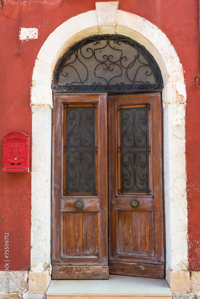 A weathered wooden door in an old red building - background