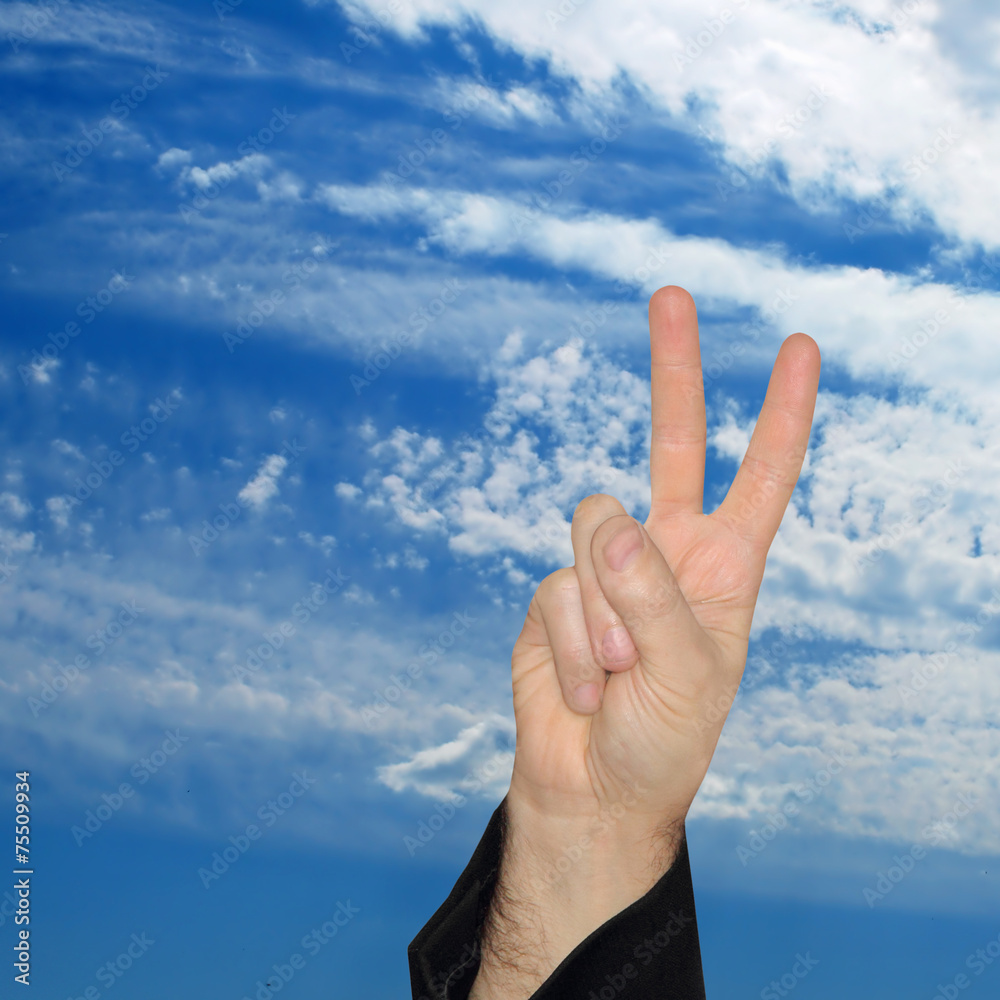 Man hand showing the victory sign on blue sky background. Man hand showing the victory sign on blue sky background.