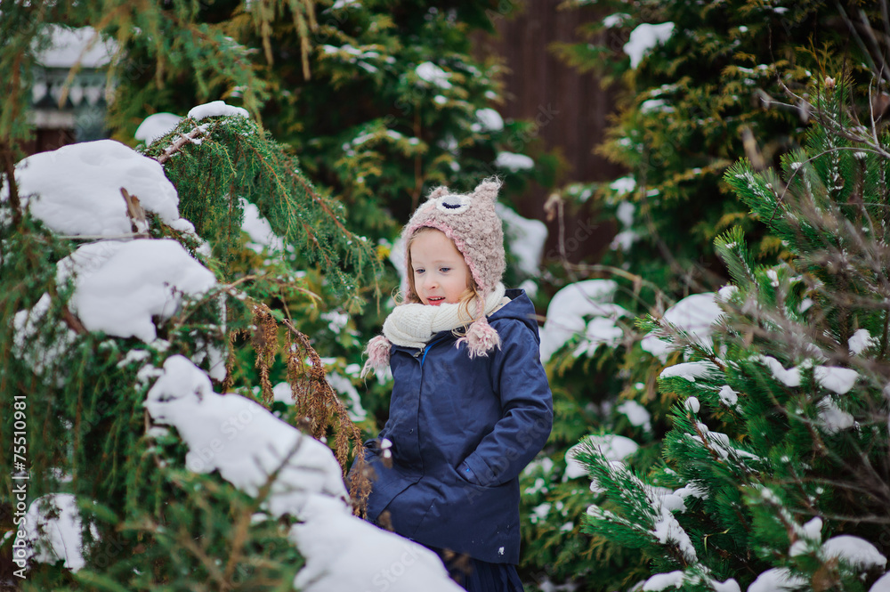 cute happy child girl in winter snowy garden