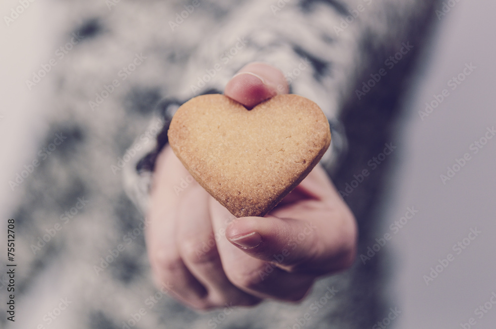 Obraz premium Woman holding a heart shaped butter biscuit. Valentine's day
