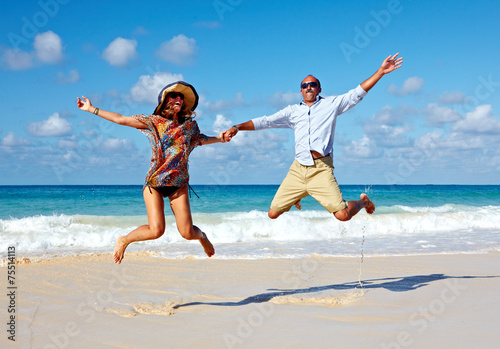 Happy couple jumping on the beach.