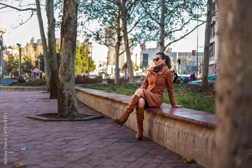 Fashionable girl sitting on a bench