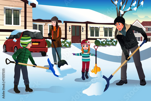 Family shoveling snow in front of their house