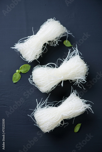 Raw bean vermicelli over black wooden background, above view