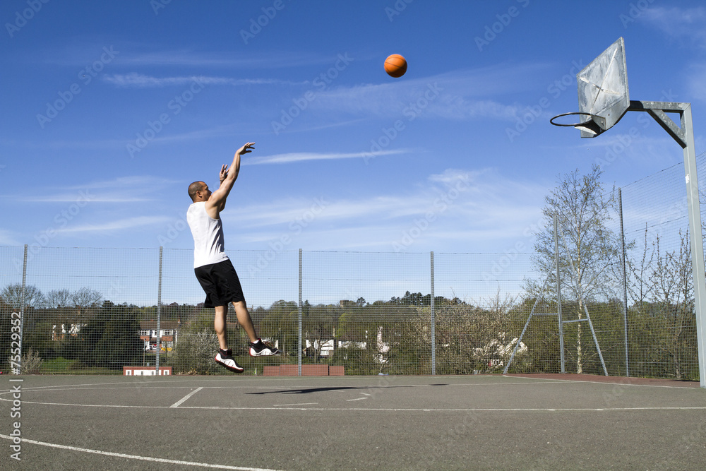 Basketball player taking a jump shot on an outdoor court