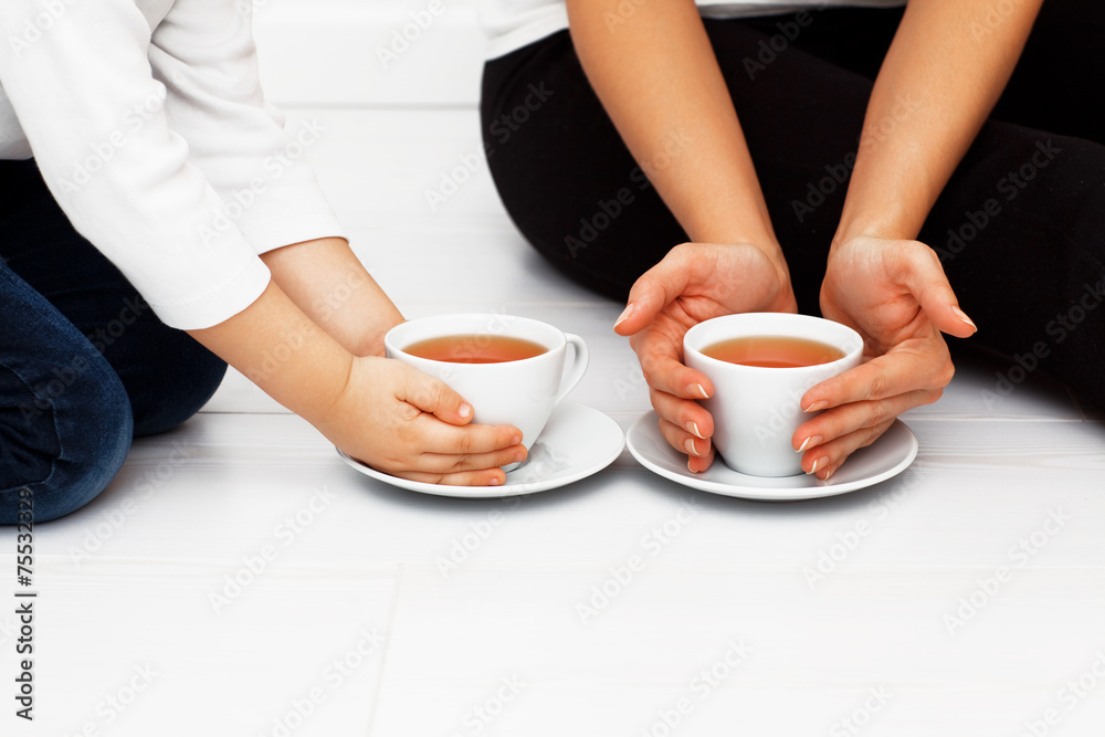 Mother with child warming hands with cup of tea Mother with child warming hands with cup of tea