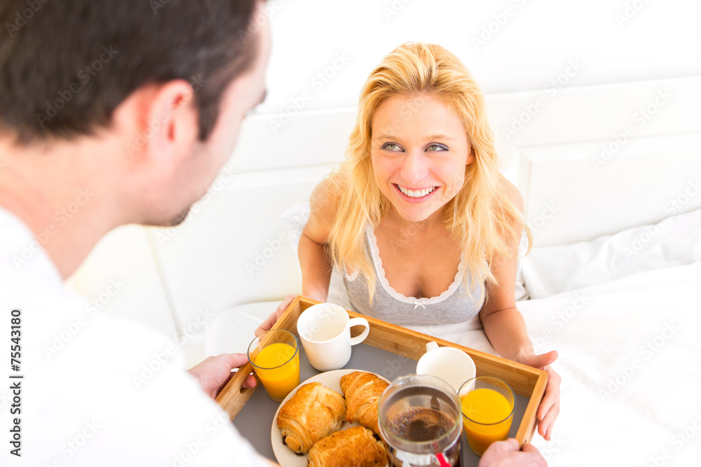 Man bringing young attractive woman breakfast in bed