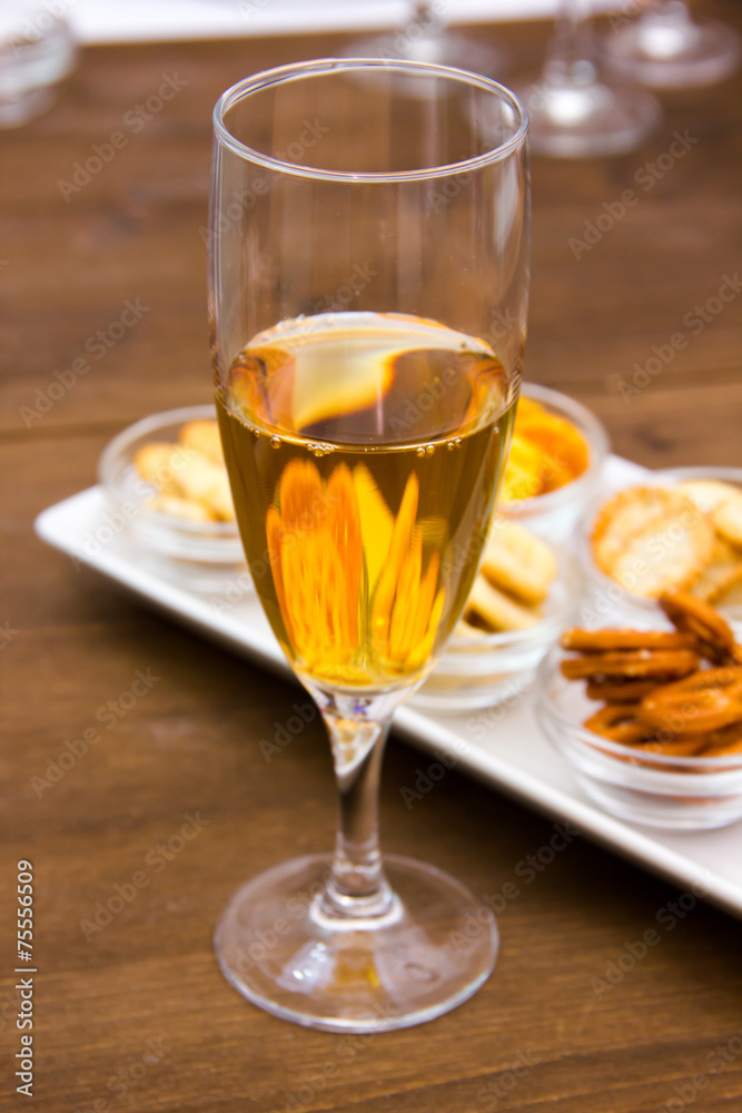 Flute with aperitif and pretzels on wooden table seen close Flute with aperitif and pretzels on wooden table seen close
