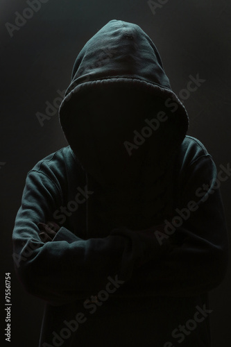 Unrecognizable person wearing hood against black background