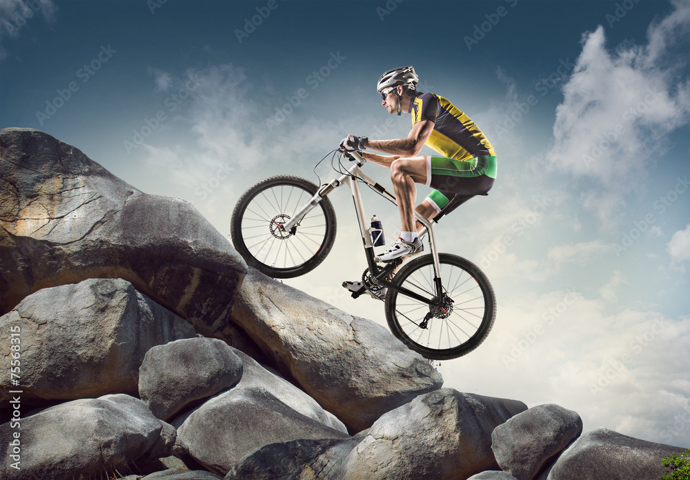 Sport background. Cyclist climbing on a rock. - obrazy, fototapety, plakaty 