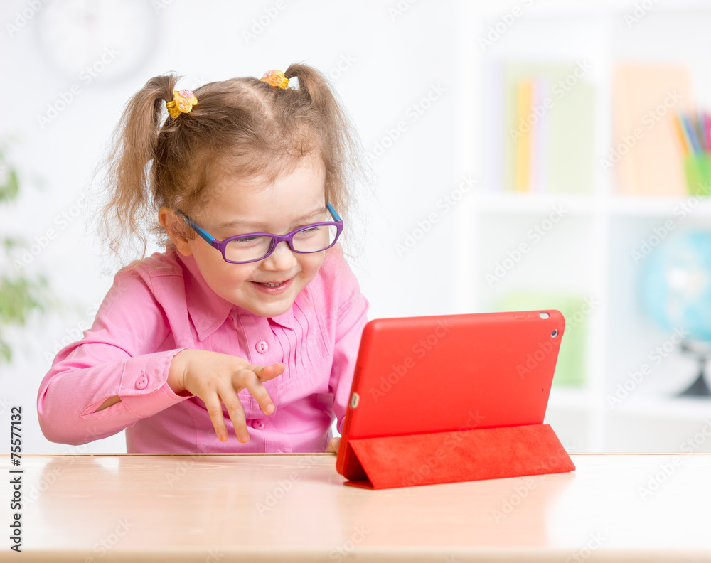 Kid with tablet PC in glasses learning with interest